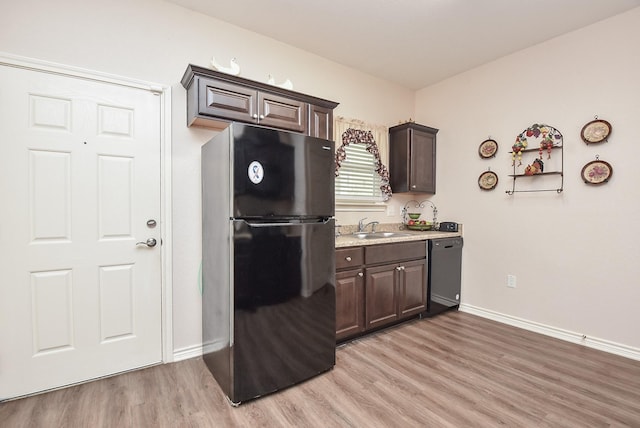 kitchen featuring light wood-type flooring, sink, dark brown cabinetry, and black appliances