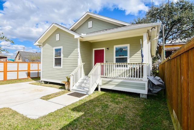 bungalow featuring covered porch and a front yard