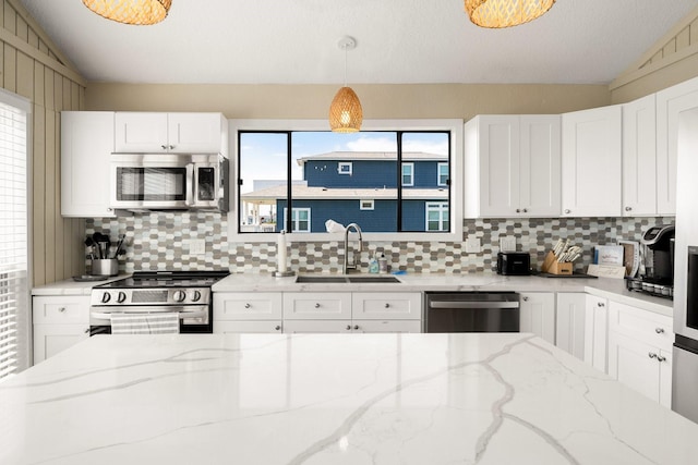 kitchen featuring pendant lighting, sink, appliances with stainless steel finishes, light stone countertops, and vaulted ceiling