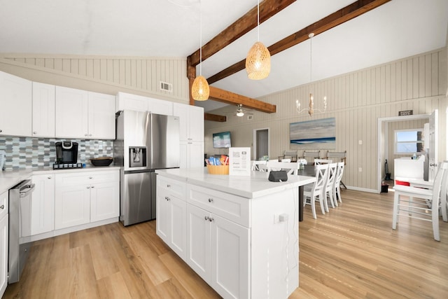 kitchen with decorative light fixtures, vaulted ceiling with beams, white cabinets, stainless steel appliances, and light hardwood / wood-style flooring