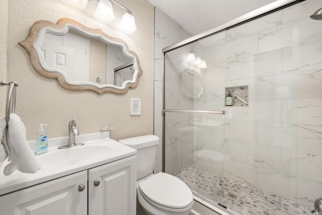 bathroom with vanity, a shower with door, and toilet