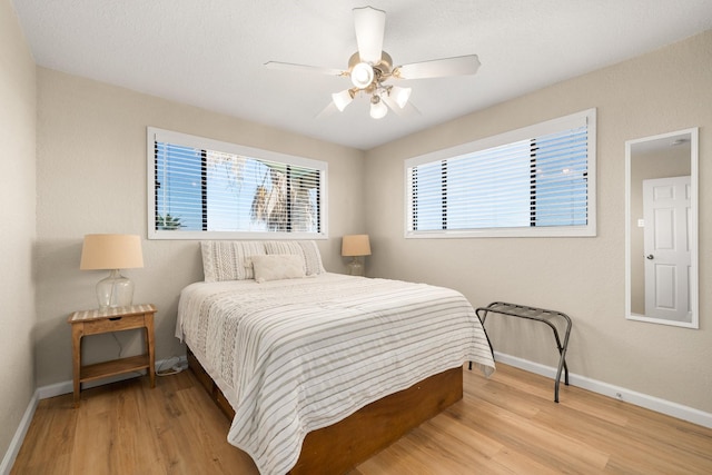 bedroom with multiple windows, light hardwood / wood-style flooring, and ceiling fan