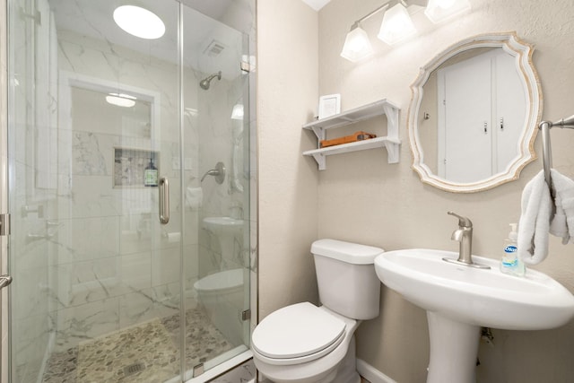 bathroom featuring toilet and a shower with shower door