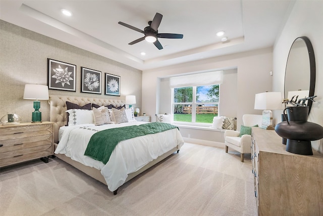 bedroom featuring light colored carpet, ceiling fan, and a tray ceiling