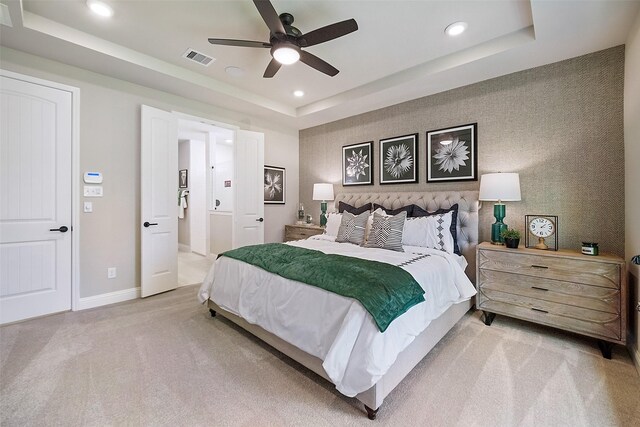 bedroom with light colored carpet, visible vents, baseboards, a tray ceiling, and wallpapered walls