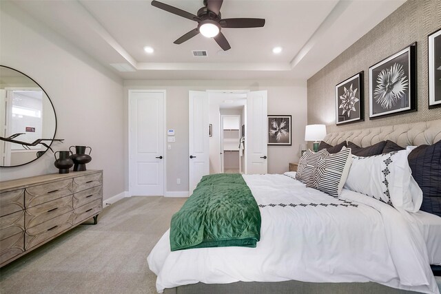 bedroom with visible vents, baseboards, light colored carpet, a tray ceiling, and recessed lighting