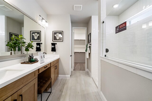 full bath with a walk in shower, a spacious closet, wood finished floors, and visible vents