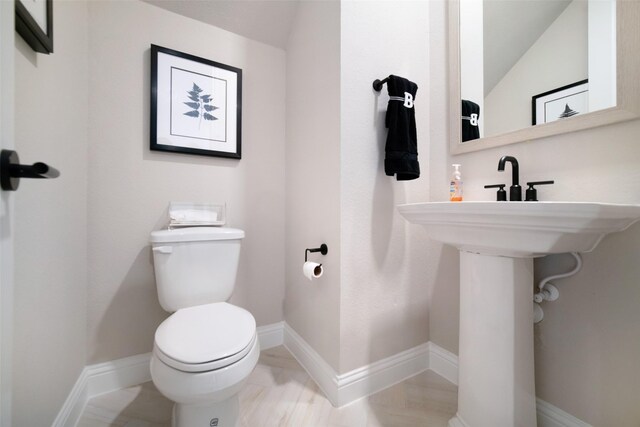 bathroom featuring toilet, baseboards, and vaulted ceiling