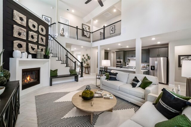 living area with ceiling fan, recessed lighting, visible vents, stairs, and a glass covered fireplace