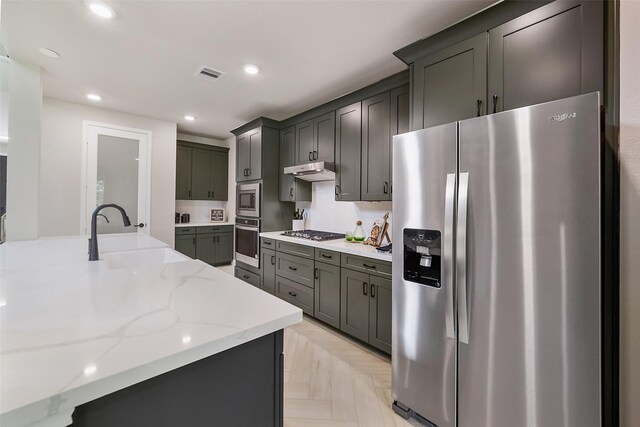 kitchen featuring visible vents, light stone countertops, stainless steel appliances, under cabinet range hood, and a sink