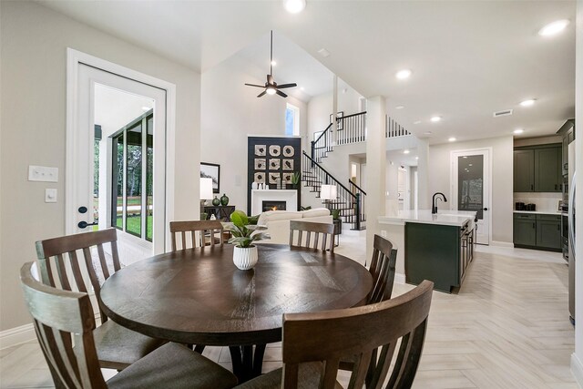 dining area featuring recessed lighting, a warm lit fireplace, stairway, and baseboards