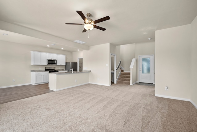 unfurnished living room with ceiling fan, light colored carpet, and sink