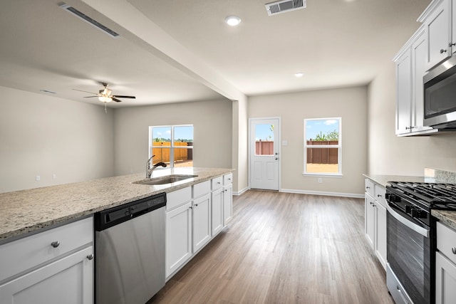 kitchen featuring stainless steel appliances, sink, white cabinets, and light stone counters