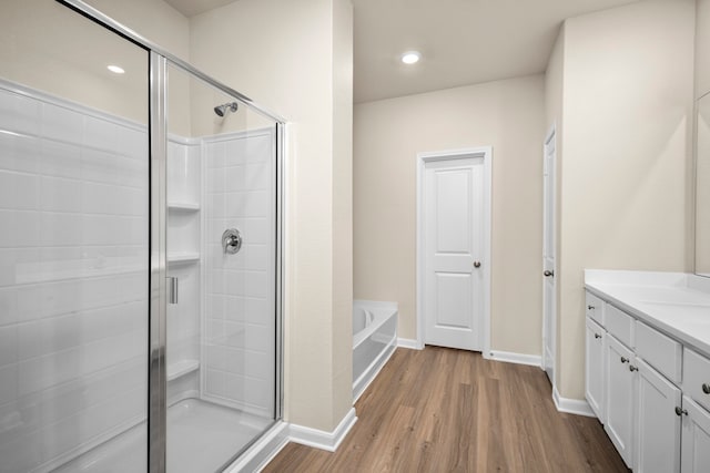 bathroom with hardwood / wood-style flooring, shower with separate bathtub, and vanity