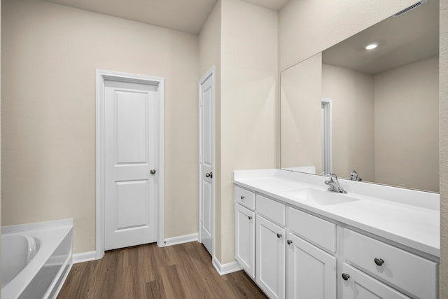 bathroom with vanity, hardwood / wood-style floors, and a bathtub