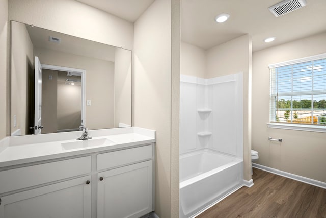 full bathroom with vanity, bathing tub / shower combination, hardwood / wood-style floors, and toilet