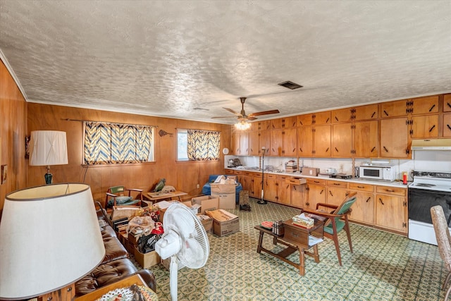 kitchen featuring ceiling fan, white appliances, wooden walls, and a textured ceiling