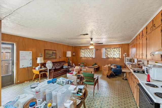 interior space featuring a textured ceiling, ceiling fan, and wood walls