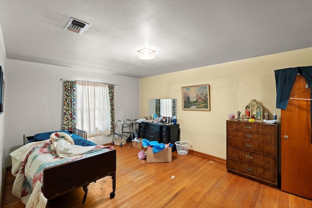 bedroom featuring light hardwood / wood-style flooring and a textured ceiling