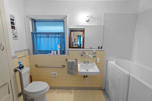 bathroom featuring tile patterned floors, toilet, sink, and tile walls