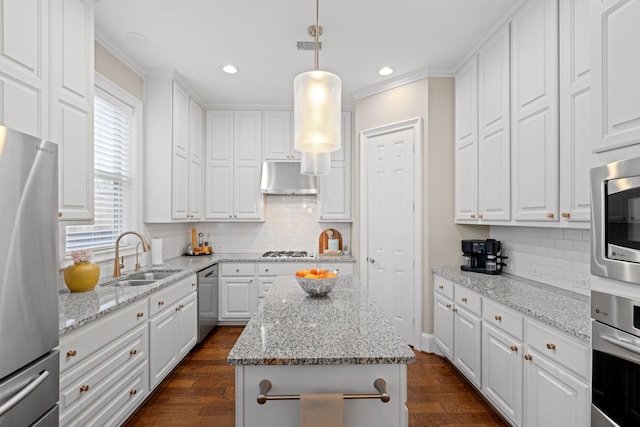 kitchen with sink, decorative light fixtures, appliances with stainless steel finishes, a kitchen island, and white cabinets