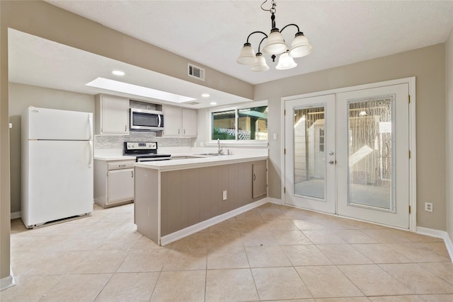 kitchen featuring decorative backsplash, hanging light fixtures, kitchen peninsula, stainless steel appliances, and french doors