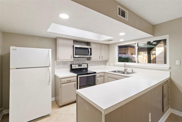 kitchen featuring sink, a skylight, appliances with stainless steel finishes, kitchen peninsula, and decorative backsplash