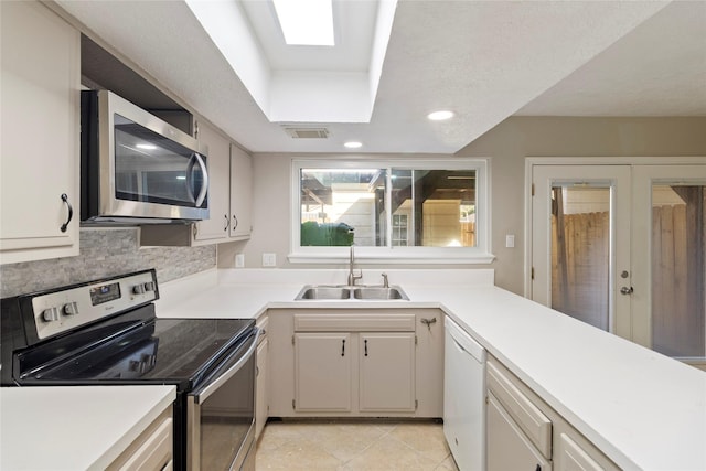 kitchen featuring tasteful backsplash, white cabinetry, appliances with stainless steel finishes, and sink