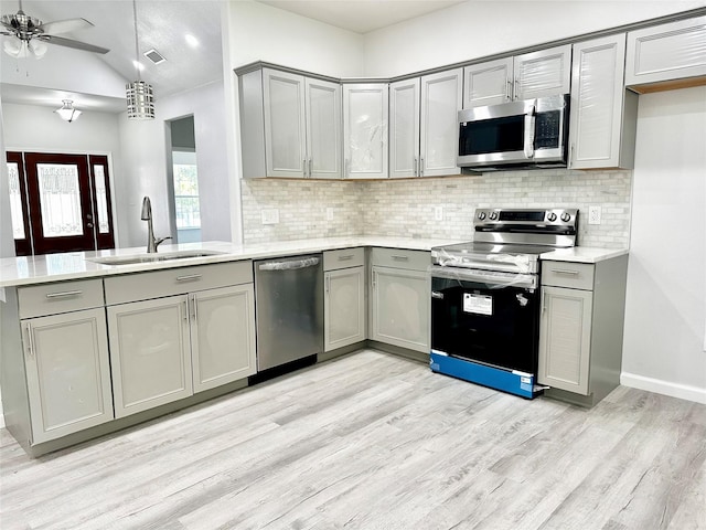 kitchen featuring stainless steel appliances, sink, kitchen peninsula, and gray cabinets