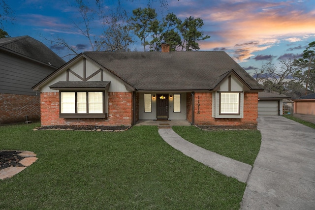 tudor-style house featuring a garage and a yard