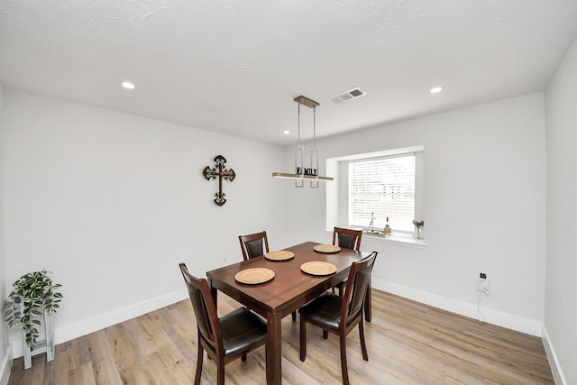 dining room with light hardwood / wood-style flooring and a textured ceiling