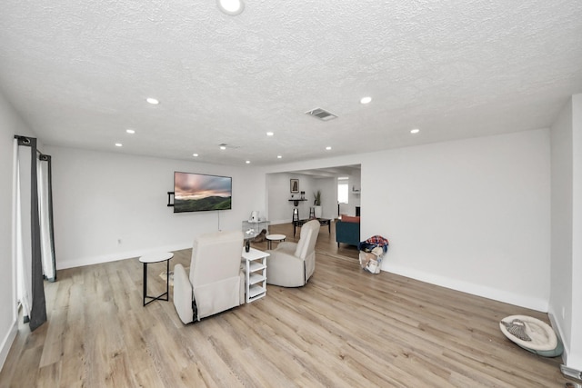 living room featuring a textured ceiling and light hardwood / wood-style floors