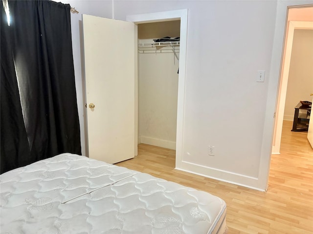 bedroom with light hardwood / wood-style floors and a closet