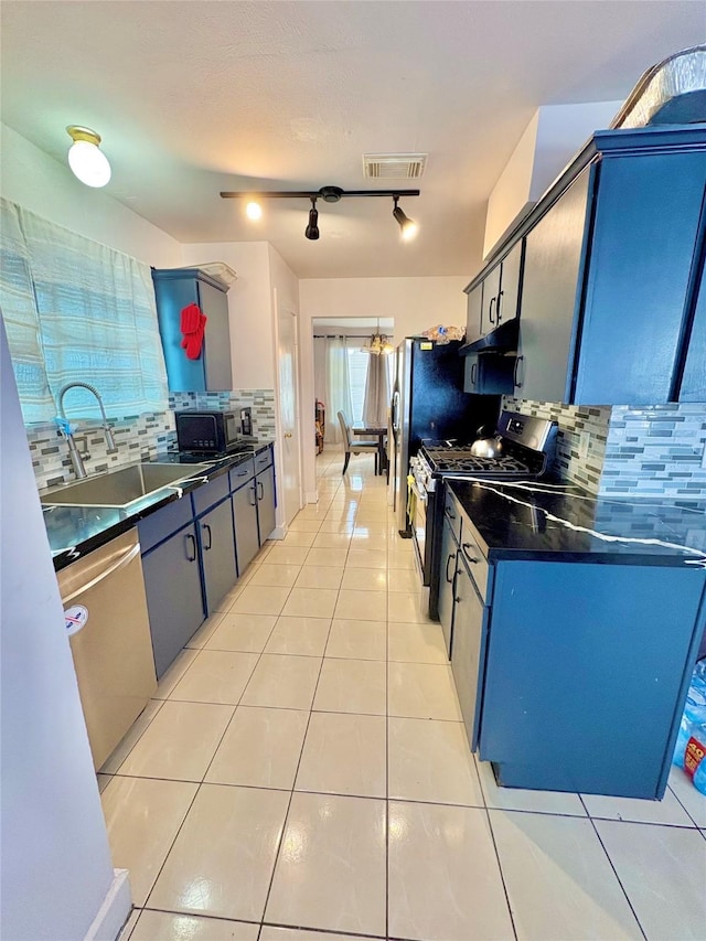 kitchen featuring light tile patterned flooring, blue cabinetry, sink, stainless steel appliances, and decorative backsplash