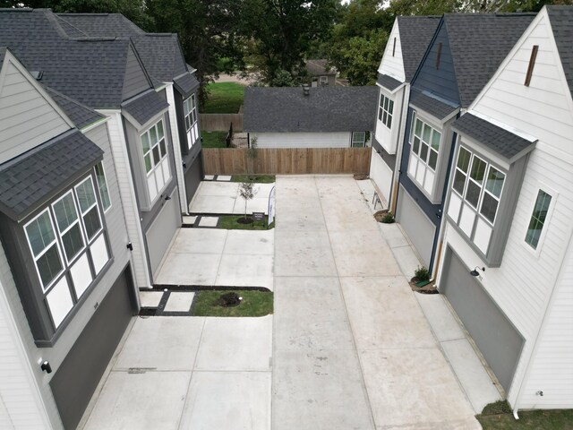 view of home's exterior with a patio, fence, and a shingled roof