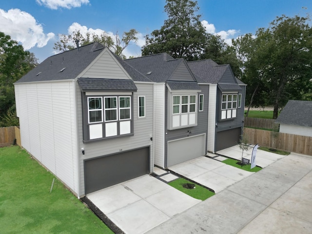 view of front facade with fence, a shingled roof, a garage, a front yard, and driveway