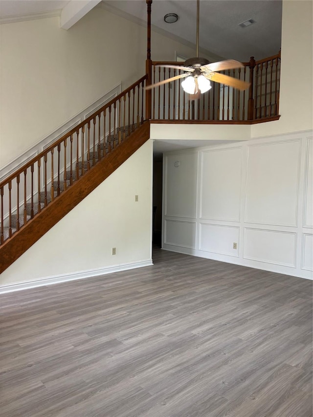 unfurnished living room featuring hardwood / wood-style floors, beam ceiling, high vaulted ceiling, and ceiling fan