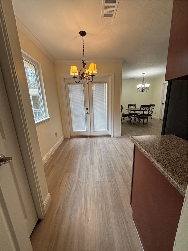 unfurnished dining area with ornamental molding, light wood-type flooring, and an inviting chandelier