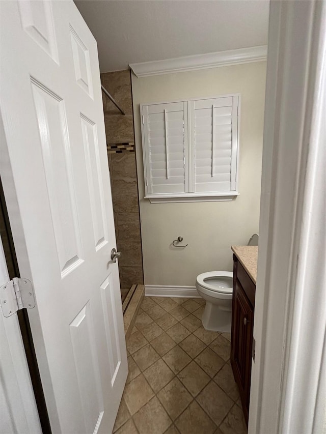 bathroom with a tile shower, vanity, ornamental molding, and toilet