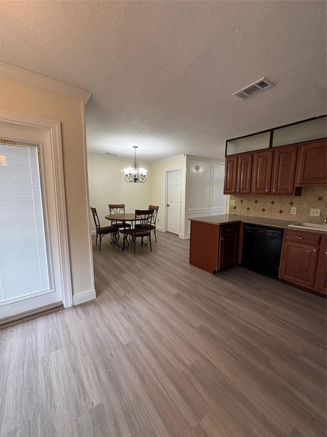 kitchen featuring a textured ceiling, hanging light fixtures, light hardwood / wood-style flooring, dishwasher, and decorative backsplash