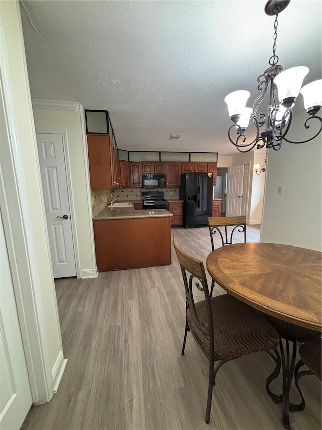 dining room with an inviting chandelier, sink, light hardwood / wood-style flooring, and a textured ceiling