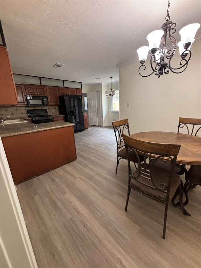 dining area featuring a notable chandelier, light hardwood / wood-style floors, sink, and a textured ceiling