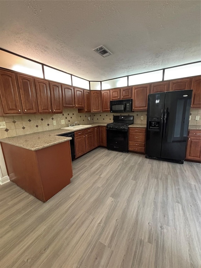 kitchen with sink, backsplash, black appliances, a textured ceiling, and light wood-type flooring