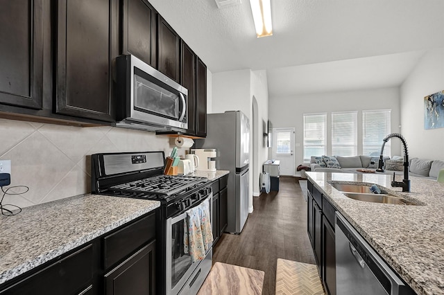 kitchen with stainless steel appliances, light stone countertops, sink, and backsplash