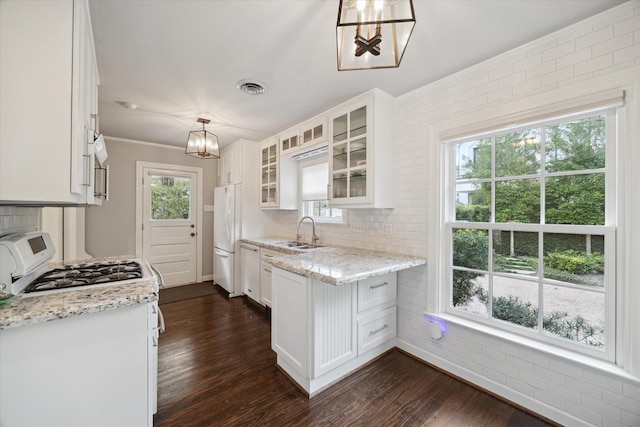 kitchen featuring white cabinetry, sink, white appliances, and decorative light fixtures