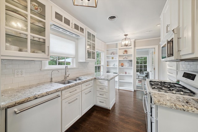 kitchen with decorative light fixtures, white cabinetry, sink, light stone counters, and stainless steel appliances