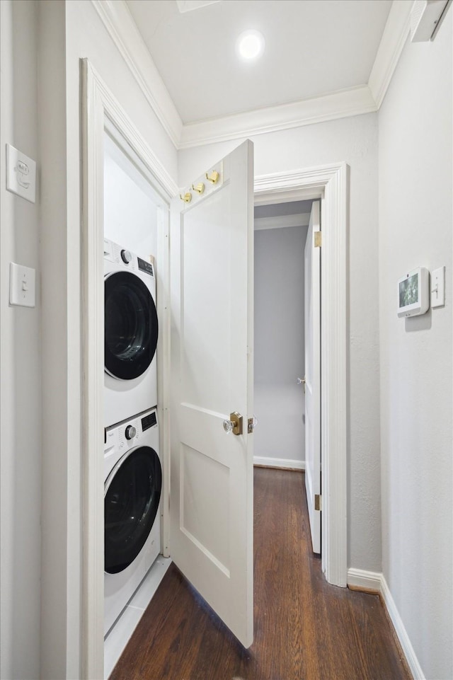 laundry area featuring crown molding, stacked washer and dryer, and dark hardwood / wood-style floors