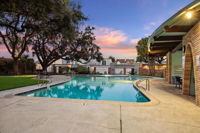 pool at dusk with a patio area