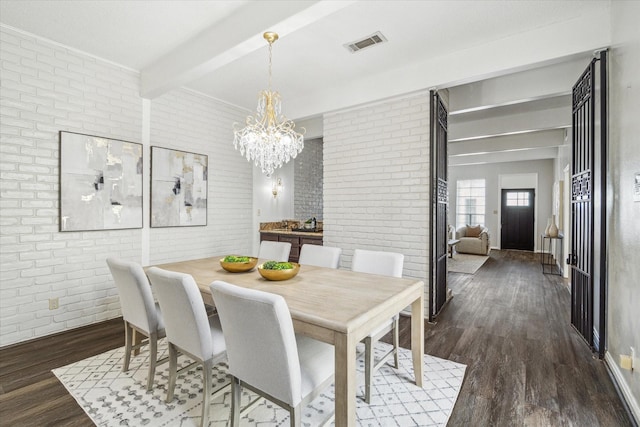 dining room featuring brick wall, dark hardwood / wood-style floors, a chandelier, and beam ceiling