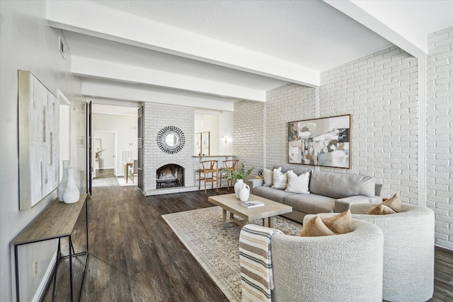 living room with dark hardwood / wood-style flooring, a fireplace, beamed ceiling, and brick wall